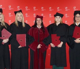 Zdjęcie absolwentów ubranych w birety i togina czerwonej ściance z logami uniwersytetu łódzkiego